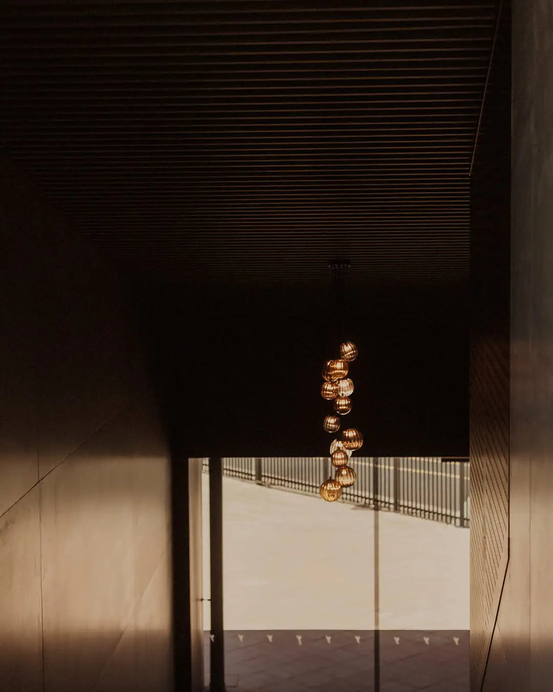 Modern chandelier hanging from a ceiling in a dimly lit room from Yangarra Cellar Door