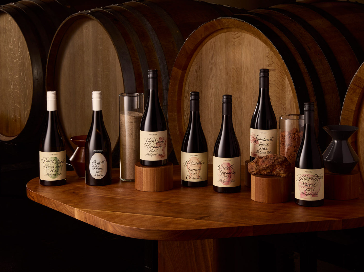 Wine bottles on a wooden table with barrels in the background