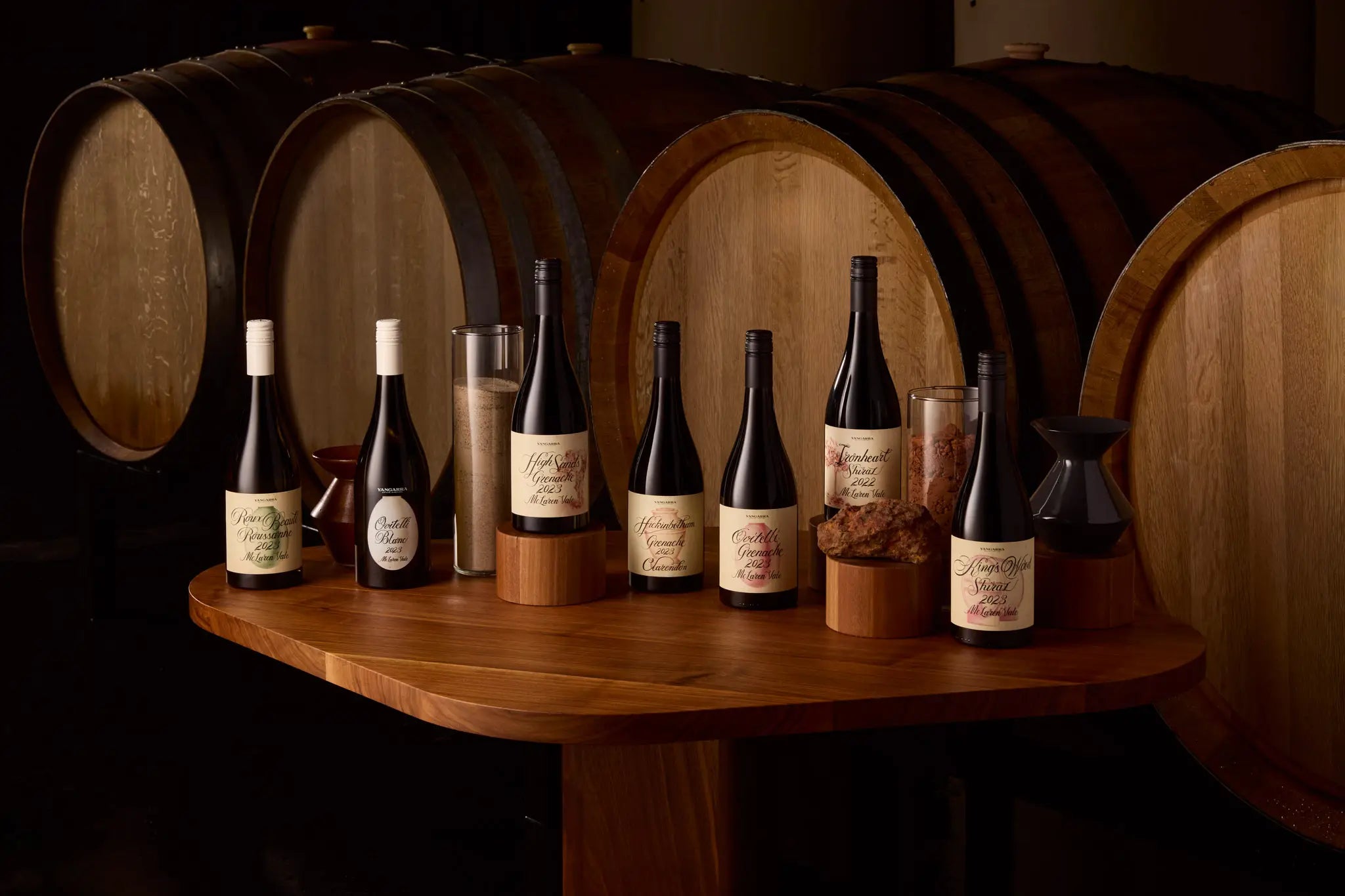 Yangarra Wine bottles on a wooden table with wine barrels in the background